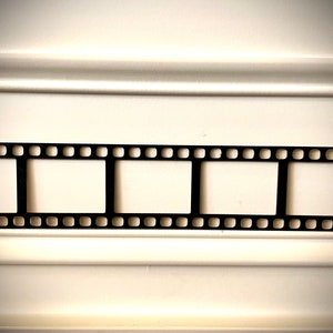 May include: A black film strip with three empty frames against a white background.
