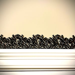 May include: A black decorative trim with a detailed, intricate, and ornate design. The trim is made of a thin, lightweight material and has a delicate, lacy appearance.