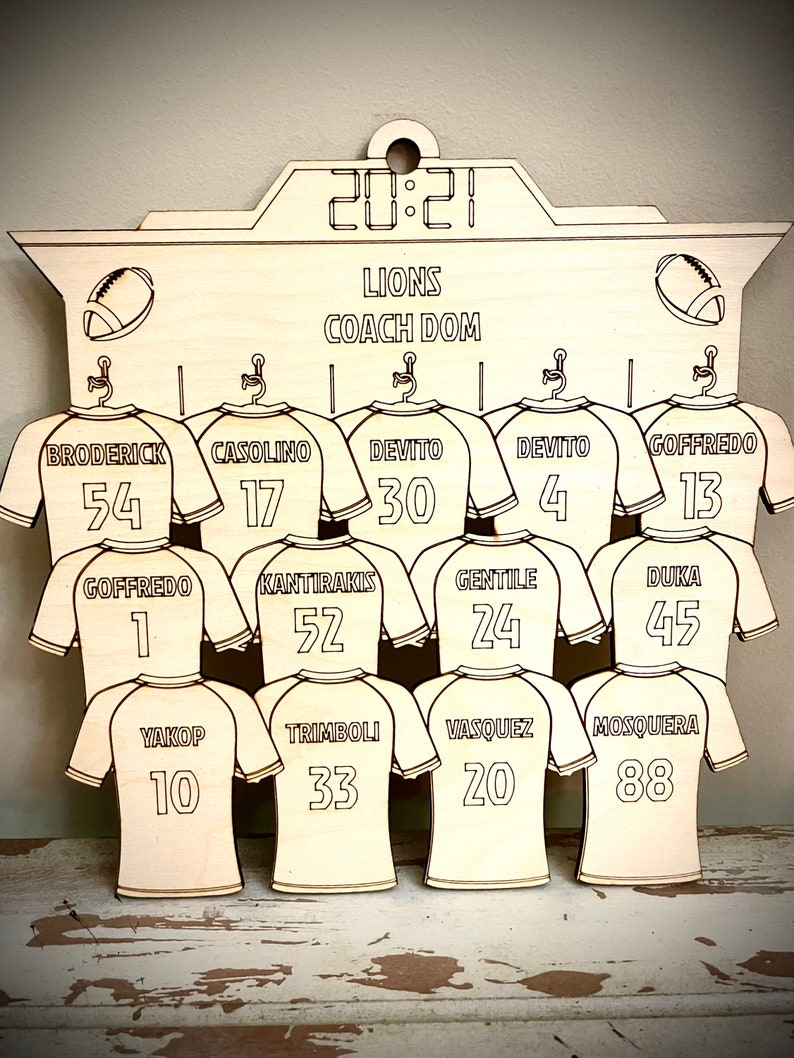 May include: A wooden sign with a scoreboard design featuring the word "LIONS" and "COACH DOM" with a football jersey for each player on the team. The jerseys have numbers from 1 to 88.