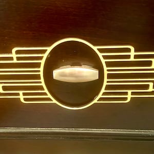 May include: A gold-colored drawer pull with a geometric design and a silver-colored handle.