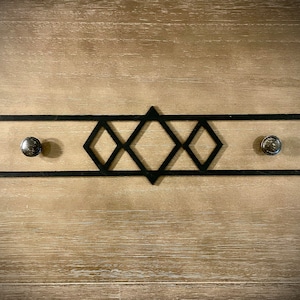 Może przedstawiać: Czarny metalowy uchwyt do szuflady z geometrycznym wzorem diamentowym i dwoma srebrnymi gałkami.