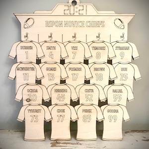 May include: A wooden sign with a scoreboard design featuring the text "RIPON NOVICE CHIEFS" and a list of names and numbers. The sign is decorated with football jerseys and footballs.