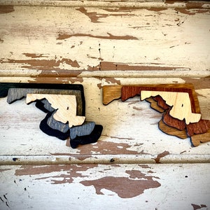 Maryland 3-layer stacked state laser cut wood magnet available in brown tones or gray tones.