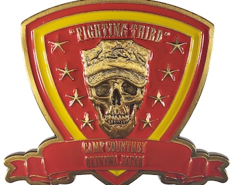 May include: A gold-colored metal pin with a red and yellow shield design. The shield features a skull wearing a military hat and the text "Fighting Third". The shield is surrounded by seven stars. Below the shield is a red banner with the text "Camp Courtney Okinawa Japan".