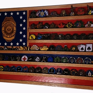 May include: A wooden shadow box with a red, white, and blue American flag design. The shadow box has multiple shelves for displaying challenge coins. The top shelf features a Pennsylvania State Police badge.