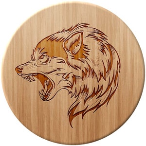Könnte beinhalten: Ein Untersetzer aus Holz mit einem lasergravierten Design eines Wolfskopfes mit offenem Maul im Knurren. Der Wolf blickt zur linken Seite des Bildes.