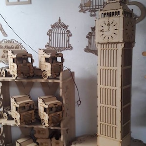 Peut inclure: Un modèle en bois du Big Ben, la célèbre tour de l'horloge de Londres, en Angleterre. Le modèle est détaillé et comprend un cadran d'horloge avec des chiffres romains. Le modèle est sur une base en bois et est entouré d'autres modèles en bois de camions.