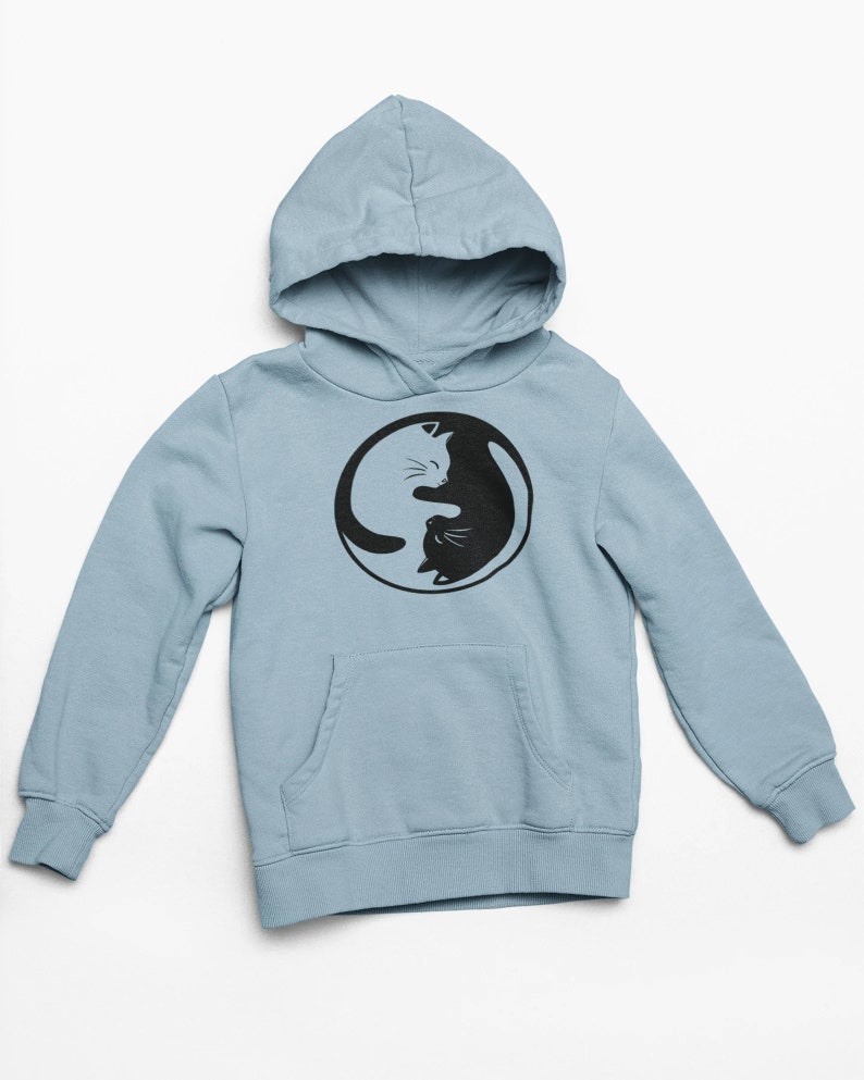 May include: A light blue hoodie with a black and white Yin Yang cat design. The hoodie features a hood, a front pocket, and long sleeves. The cat design is in a circular shape.