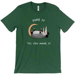 K&ouml;nnte beinhalten: Dunkelgr&uuml;nes T-Shirt mit dem Text "FAKE IT 'TIL YOU MAKE IT" und einem Cartoon-Opossum. Das Opossum ist grau mit einem beigen Schwanz und rosa F&uuml;&szlig;en. Das T-Shirt ist aus einem weichen Material.
