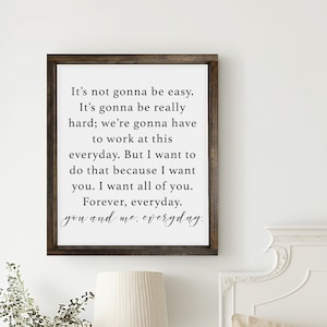 May include: A white wooden sign with a black inscription that reads "It's not gonna be easy. It's gonna be really hard; we're gonna have to work at this everyday. But I want to do that because I want you. I want all of you. Forever, everyday. you and me, everyday."
