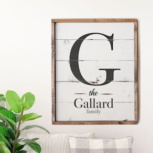 May include: A white wooden sign with a black letter G and the text "the Gallard family" in black lettering.