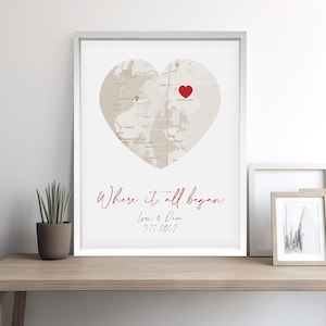 May include: A white framed print with a beige heart-shaped map and a red heart marking a location. The text "Where it all began" is written in cursive with the names "Lori & Dave" and the date "3.11.2017" below.
