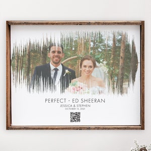 May include: A framed wedding photo featuring a couple with a waveform design overlay. The text reads "PERFECT - ED SHEERAN" with the names Jessica & Stephen and the date October 15, 2021. A QR code is also present. The frame is brown.
