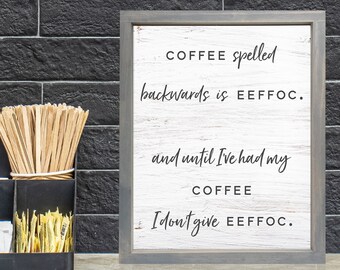May include: A framed wooden sign with the text "COFFEE spelled backwards is EEFFOC. and until I've had my COFFEE I don't give EEFFOC." is displayed on a counter. A black organizer holds coffee cups, stir sticks, and sugar packets. A wooden letter "K" is on the wall.