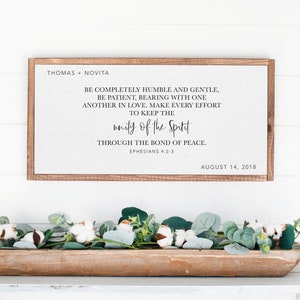 May include: A framed sign with a white background and black text. The text reads "BE COMPLETELY HUMBLE AND GENTLE, BE PATIENT, BEARING WITH ONE ANOTHER IN LOVE. MAKE EVERY EFFORT TO KEEP THE UNITY OF THE SPIRIT THROUGH THE BOND OF PEACE. EPHESIANS 4:2-3 AUGUST 14, 2018".