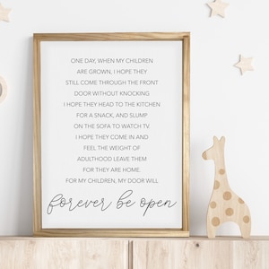 May include: A framed print with a white background and black text. The text reads: "One day, when my children are grown, I hope they still come through the front door without knocking. I hope they head to the kitchen for a snack, and slump on the sofa to watch TV. I hope they come in and feel the weight of adulthood leave them for they are home. For my children, my door will forever be open."