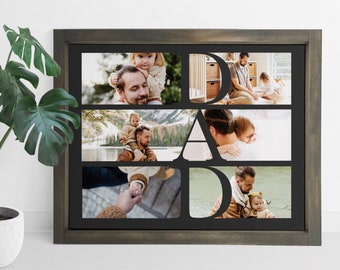 May include: A framed photo collage with the word "DAD" cut out, displaying family photos. The frame is dark gray, and the photos show a father with his child. The collage is displayed on a white background.