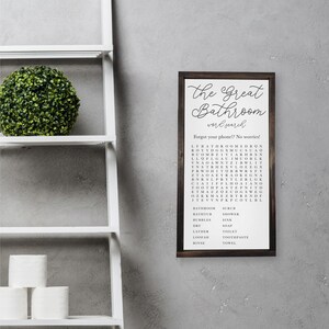 Puede incluir: Un letrero de madera marr&oacute;n con las palabras "The Great Bathroom Word Search" impresas en &eacute;l. El letrero presenta un crucigrama de palabras con las palabras "bathroom", "bathtub", "bubbles", "dry", "lather", "loofah", "rinse", "scrub", "shower", "sink", "soap", "toilet", "toothpaste" y "towel".