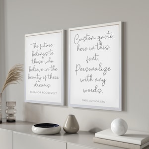 May include: Two framed prints with inspirational quotes. The left print features a quote by Eleanor Roosevelt: "The future belongs to those who believe in the beauty of their dreams." The right print is a customizable quote with the text: "Custom quote here in this font. Personalize with any words. DATE, AUTHOR, ETC"