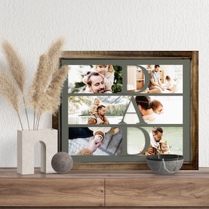 Op de afbeelding: Een ingelijste fotocollage met het woord "DAD" in grote letters. De collage bevat meerdere familiefoto's van een vader en kind. De lijst is donkerbruin en de achtergrond is een gedempt groen.