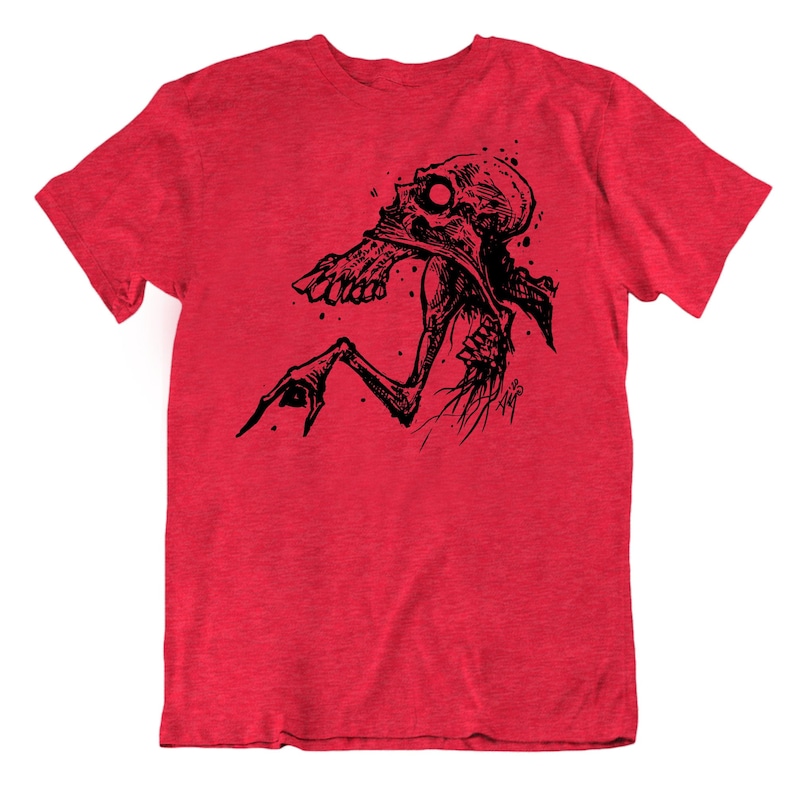Peut inclure: T-shirt rouge avec une illustration noire d'une figure squelettique. Le design pr&eacute;sente une t&ecirc;te en forme de cr&acirc;ne et un bras tendu. Le graphisme est d&eacute;taill&eacute; et artistique, avec une esth&eacute;tique grunge. Le t-shirt est en tissu doux et textur&eacute;.