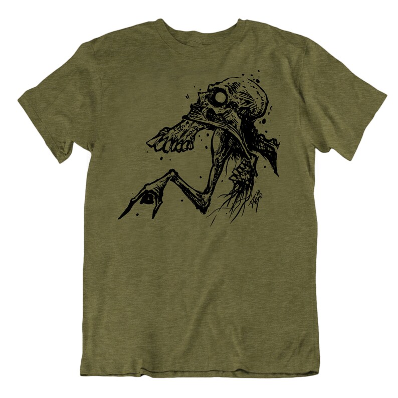 Peut inclure: T-shirt vert olive avec une illustration noire d'une cr&eacute;ature squelettique. Le dessin pr&eacute;sente une cr&eacute;ature d&eacute;taill&eacute;e de style dessin&eacute; &agrave; la main avec une bouche ouverte et une main tendue. Le t-shirt est &agrave; col rond et &agrave; manches courtes.