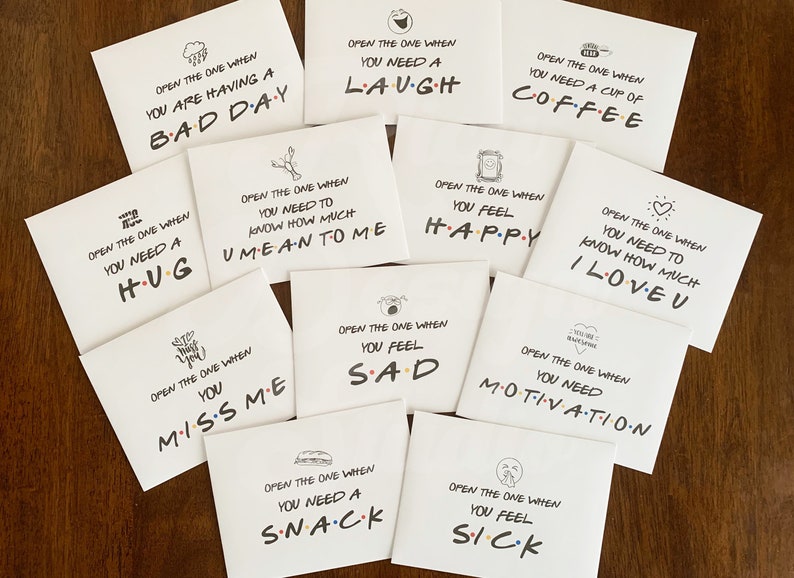 May include: Ten white cards with black text and illustrations. Each card has a different message, such as "Open the one when you need a hug" or "Open the one when you need a laugh".