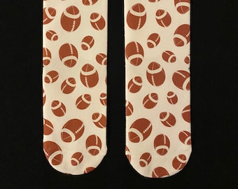May include: A pair of white socks with a brown football pattern.