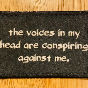 May include: Black fabric patch with white text that reads "the voices in my head are conspiring against me."