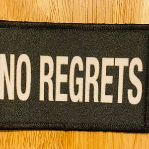 May include: Black patch with white text that reads "NO REGRETS".
