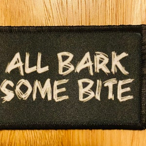 May include: Black patch with white text that reads "ALL BARK SOME BITE" in a handwritten style.