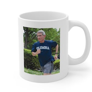 May include: White ceramic coffee mug with a photo of a person wearing a blue shirt with the word "COLUMBIA" printed on it, running outdoors.