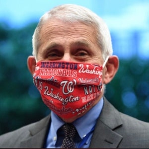 May include: A man wearing a red face mask with the words "Washington Nationals" repeated on it. The mask also features a large "W" in the center.