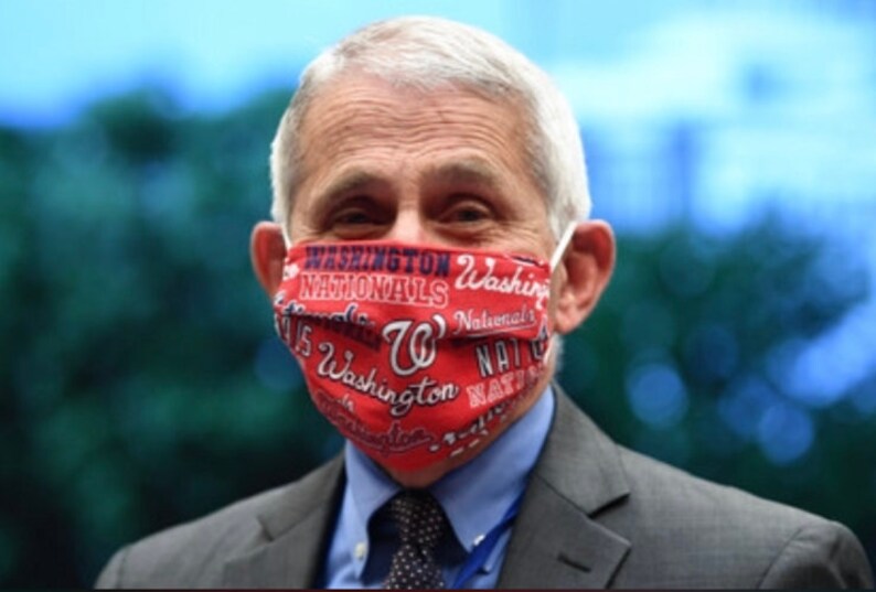 May include: A man wearing a red face mask with the words "Washington Nationals" repeated on it. The mask also features a large "W" in the center.