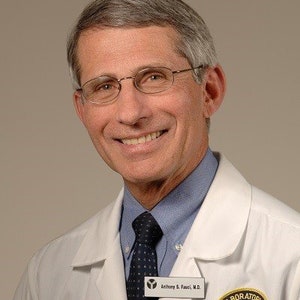 May include: A man wearing a white lab coat with a blue shirt and a dark tie. He is smiling and has a name tag that reads "Anthony S. Fauci, M.D." and a badge that reads "Laboratory of NIAID".