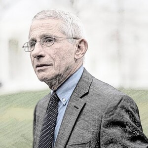 May include: A man with gray hair and a gray suit is wearing a light blue shirt and a dark blue tie with white polka dots. He is wearing glasses and has a serious expression on his face.