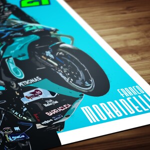 May include: A turquoise and black motorcycle with the text "PETRONAS" and "FRANCO MORBIDELLI" on it. The motorcycle is on its back wheel and the rider is leaning forward.