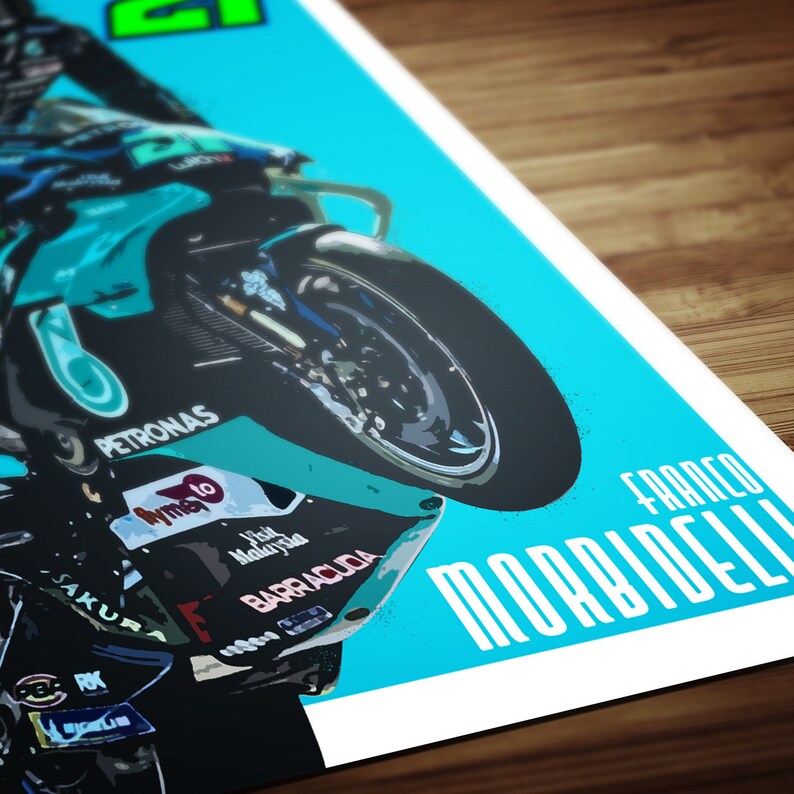 May include: A turquoise and black motorcycle with the text "PETRONAS" and "FRANCO MORBIDELLI" on it. The motorcycle is on its back wheel and the rider is leaning forward.