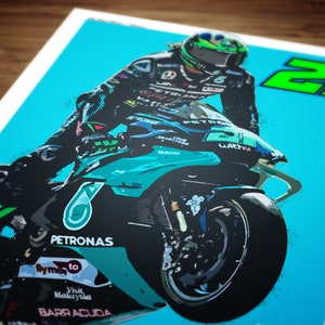 May include: A teal and black motorcycle with the number 20 on the side. The motorcycle is in mid-air with the front wheel raised. The rider is wearing a black and green racing suit and a helmet. The motorcycle has the word "PETRONAS" on the side.
