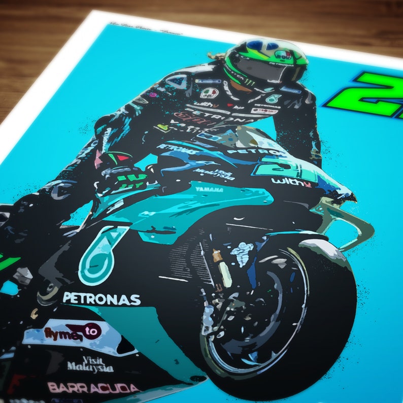 May include: A teal and black motorcycle with the number 20 on the side. The motorcycle is in mid-air with the front wheel raised. The rider is wearing a black and green racing suit and a helmet. The motorcycle has the word "PETRONAS" on the side.