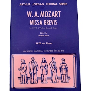 Pode incluir: Uma partitura musical vintage intitulada "W.A. Mozart Missa Brevis" da série coral Arthur Jordan. A capa é azul escuro com texto e ilustrações em rosa. A partitura é editada por Walter Ehret e publicada pela Marks Music Corporation.