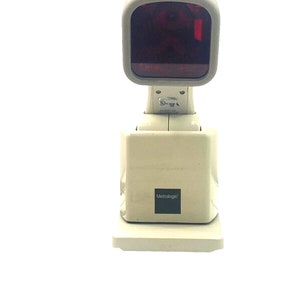 May include: A white barcode scanner with a red light on the top. The scanner is made by Metrologic.