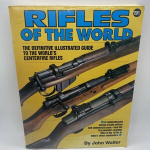 May include: A book cover with the title "Rifles of the World: The Definitive Illustrated Guide to the World's Centerfire Rifles" by John Walter. The cover features a close-up of three rifles with wooden stocks and metal barrels.