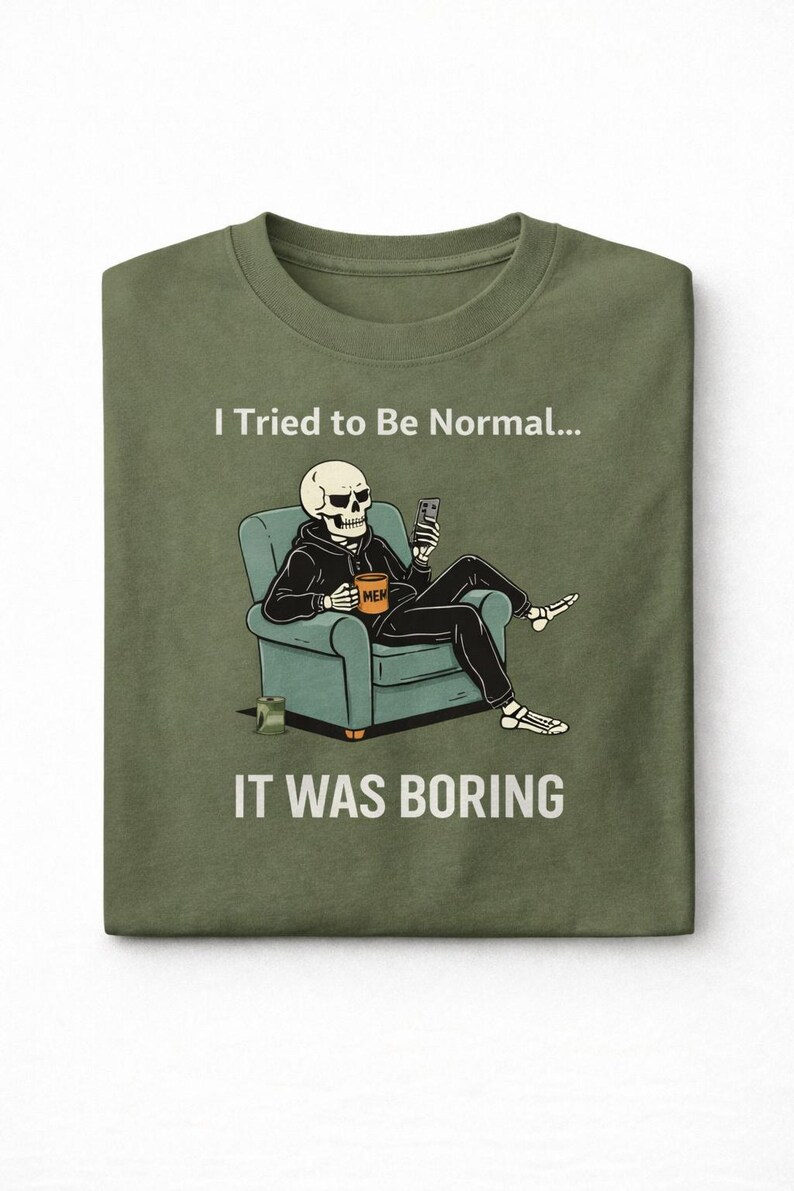 May include: Olive green t-shirt featuring a skeleton in a hoodie, seated in a teal armchair, holding a phone and a mug that says "MEM". The text "I Tried to Be Normal... IT WAS BORING" is printed above and below the illustration.