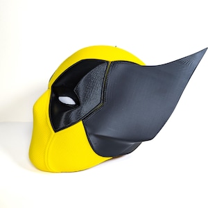 May include: A yellow and black 3D printed mask with a pointed ear. The mask is designed to look like a superhero character.