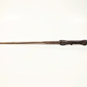 Peut inclure: Une baguette en bois brun avec une poignée brun foncé. La baguette mesure environ 30 cm de long.