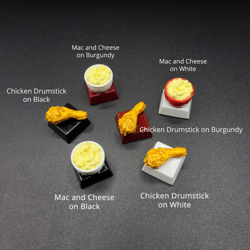 May include: Miniature food items including mac and cheese and chicken drumsticks. The mac and cheese is in small white or red bowls. The chicken drumsticks are golden brown. The items are on black, burgundy, and white platforms. Text on the image reads "Mac and Cheese" and "Chicken Drumstick".