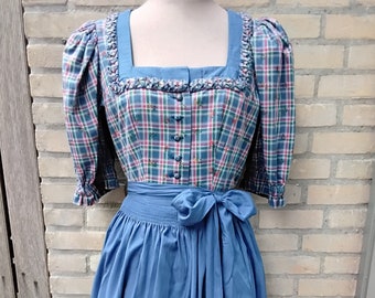 May include: A blue and green plaid dirndl dress with a white bodice and a blue skirt. The dress has a white lace trim and a bow at the waist.