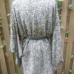 May include: A black and white patterned kimono with a green belt. The pattern is abstract and resembles a maze.