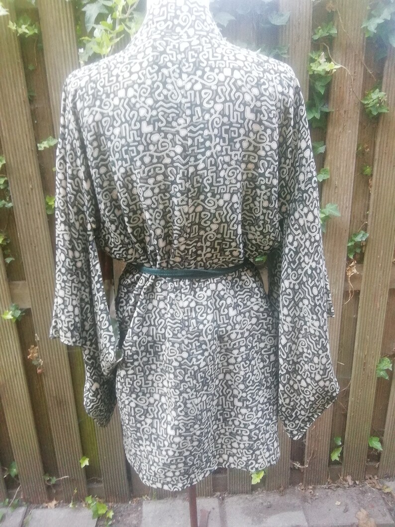 May include: A black and white patterned kimono with a green belt. The pattern is abstract and resembles a maze.